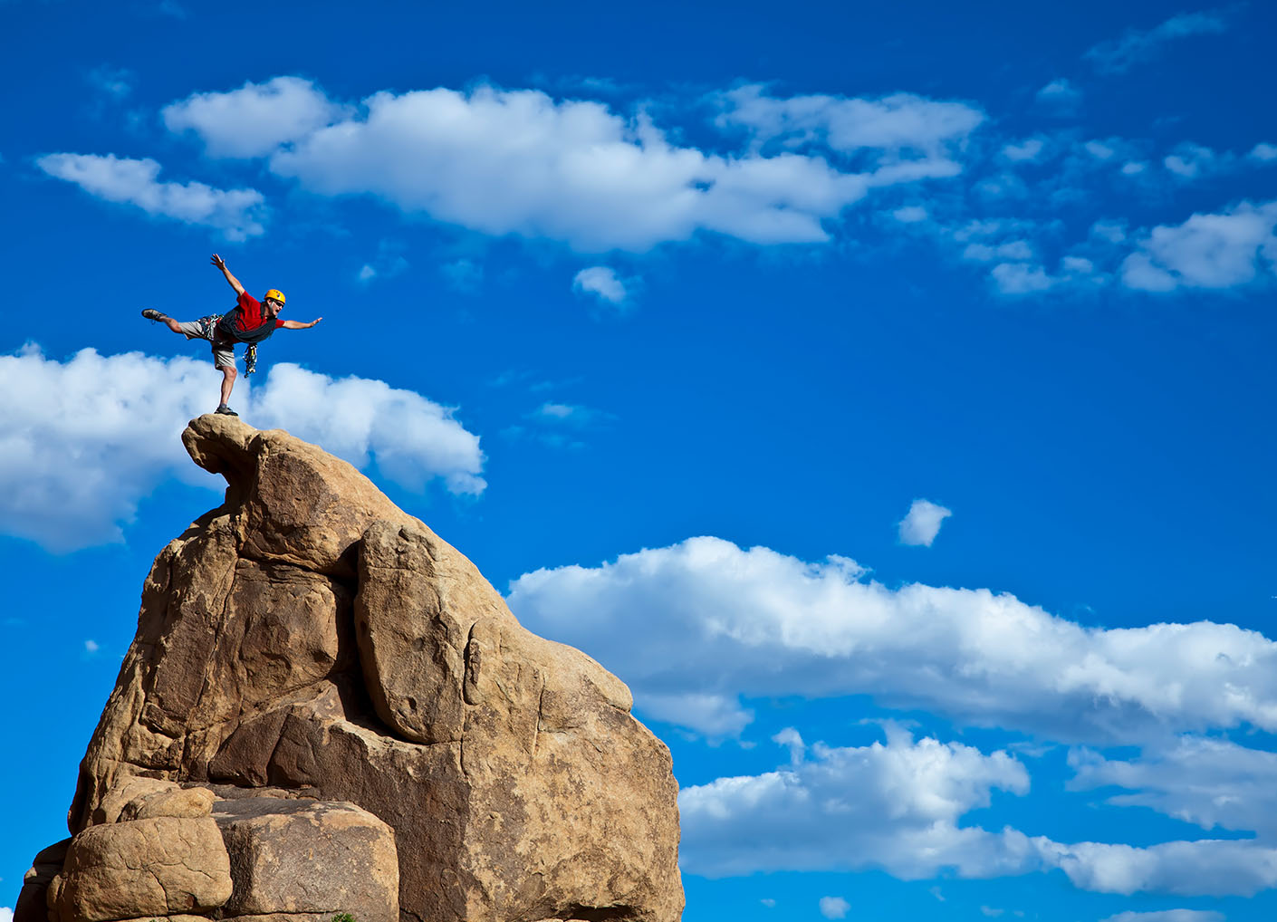 Person balancing on rock on top of mountain