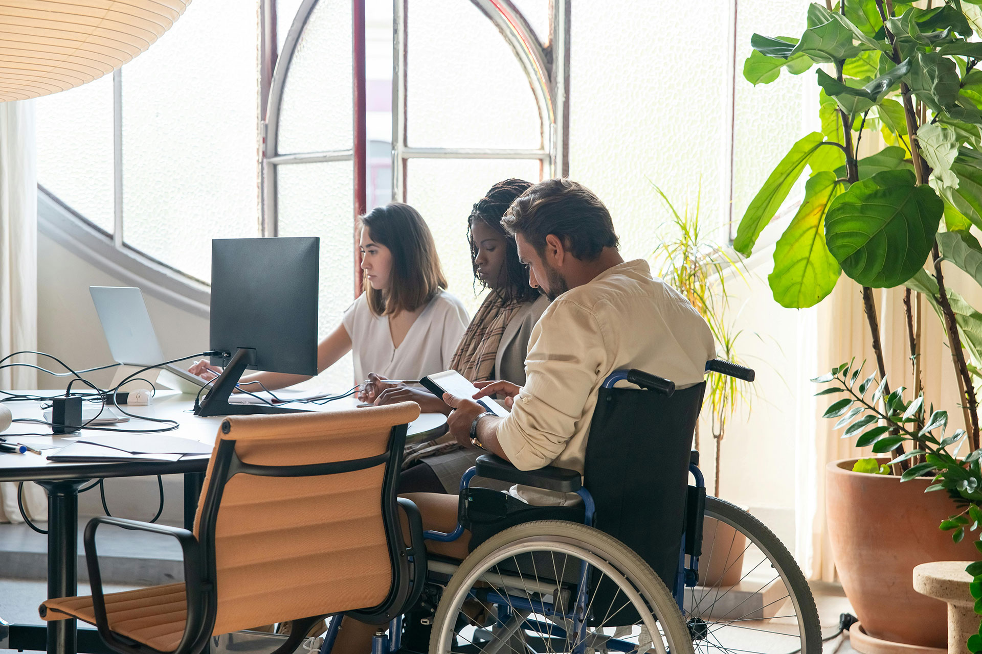 Workers sitting at a desk with one worker in wheelchair